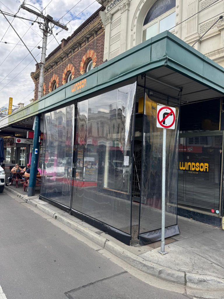 Our Cafe Crank blinds in marine grade Clear PVC create an enclosed space for our clients to use year round and maximise their venue capacity. A heavy duty base-rail with stainless steel fixings ensures protection in Melbourne's cold and windy conditions. The incorporation of a velcro strip allows custom infill panels to be fixed to the blinds to create a completely enclosed area.